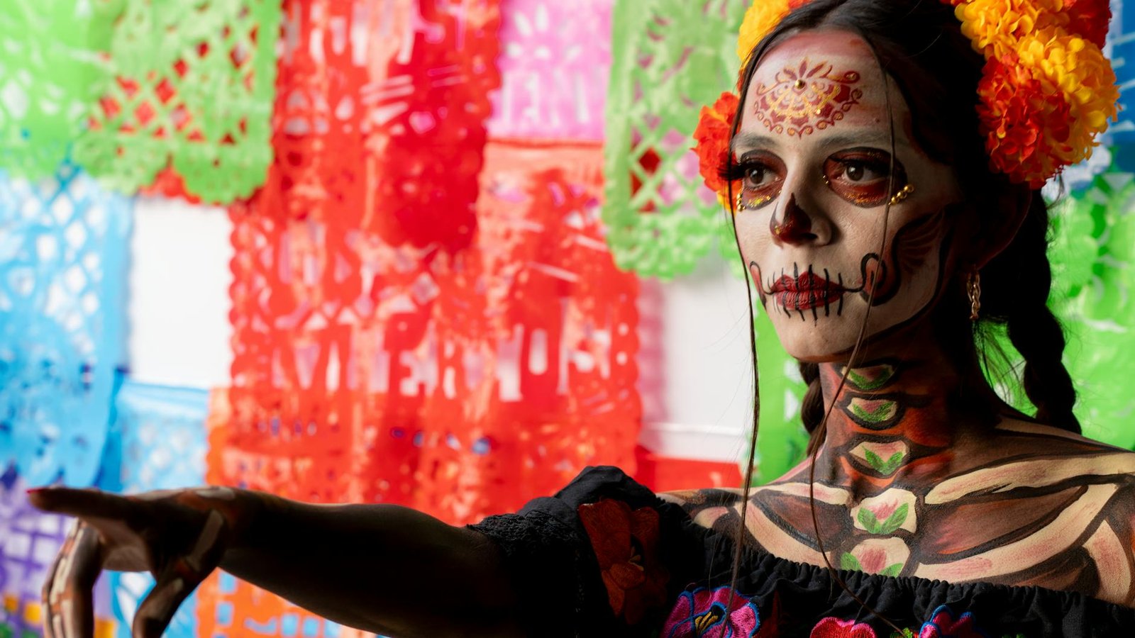 Vibrant portrait of a woman with traditional Dia de los Muertos makeup and decor.