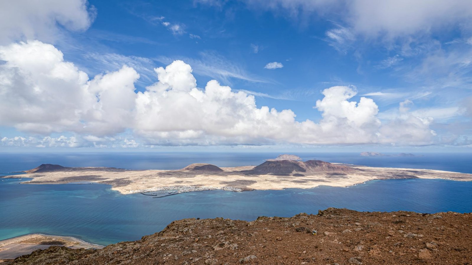 A breathtaking aerial view of La Graciosa Island's coastline with its volcanic landscape meeting the vibrant sea.