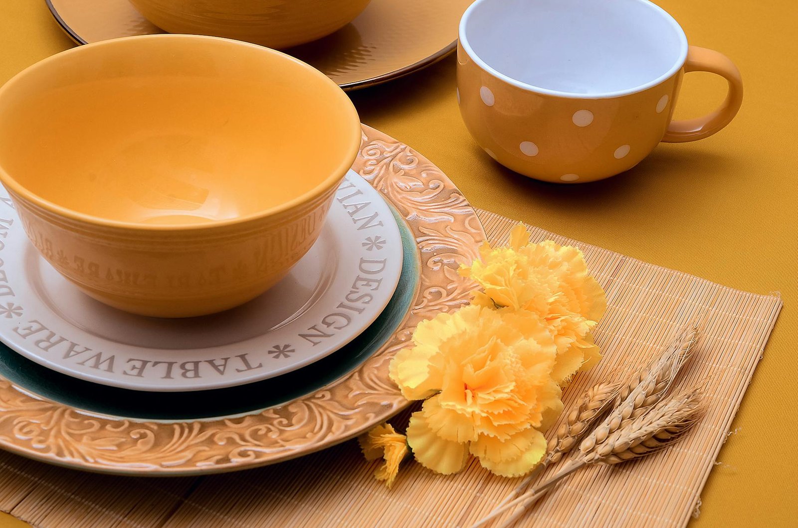 An elegant yellow-themed tableware setting with ceramic bowls and flowers.