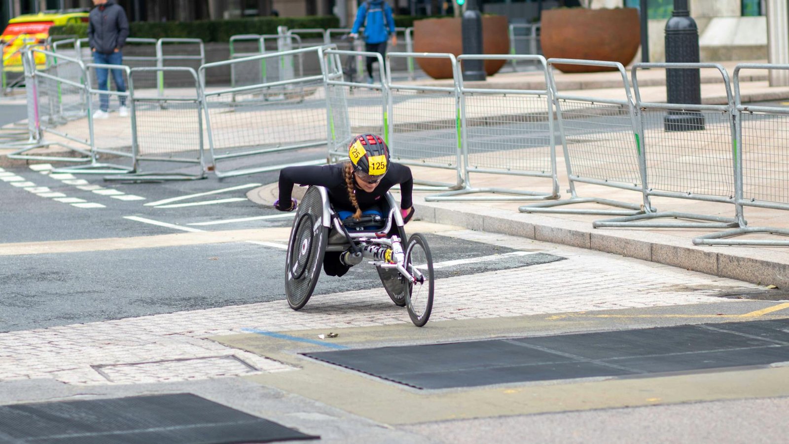 A dedicated athlete competes in a marathon using a racing wheelchair on city streets.