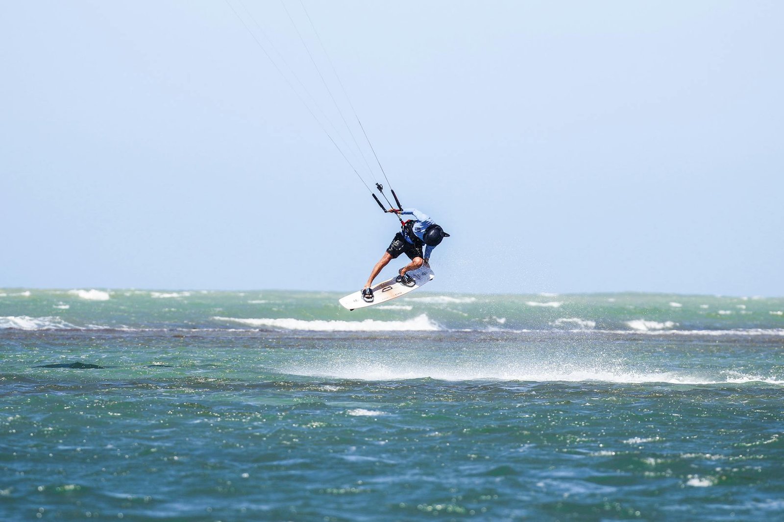 Dynamic kitesurfing action over ocean waves in Adicora, capturing the thrill of summer water sports.
