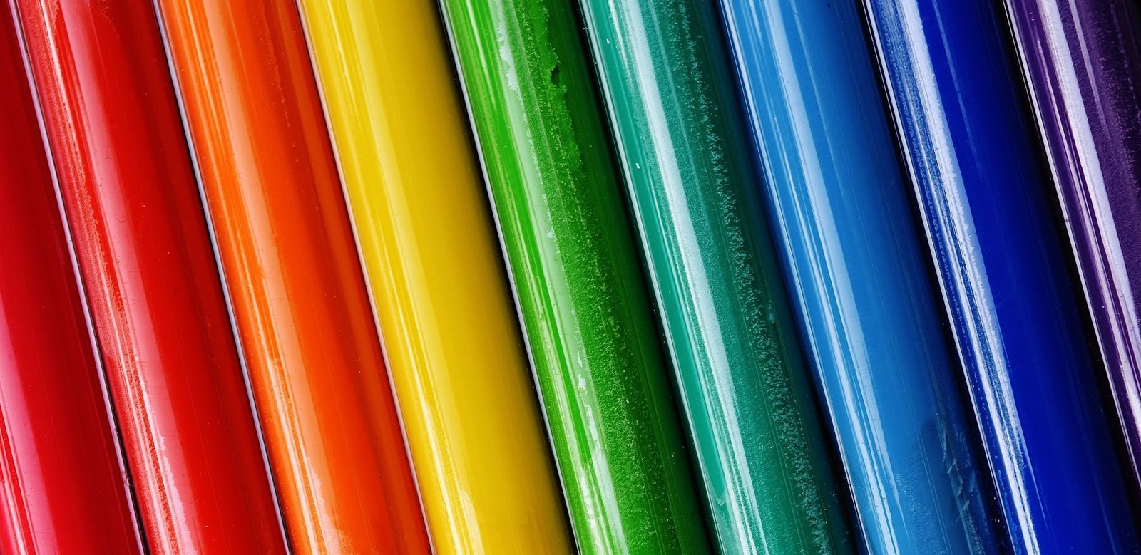 Close-up of brightly colored paint tubes arranged in a rainbow pattern.