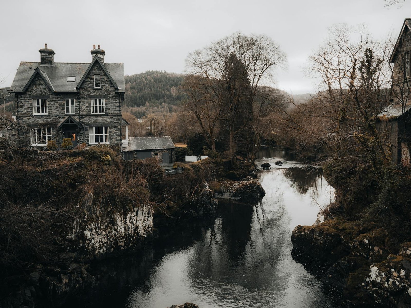 Picturesque old stone house by a tranquil river in Betws-y-Coed, Wales.