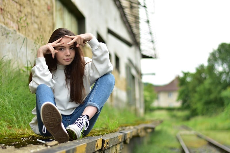 woman in white long sleeve shirt and blue denim jeans sitting on brown wooden bench during