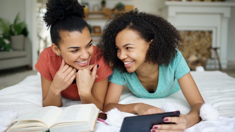Two smiling young women looking at a smartphone.