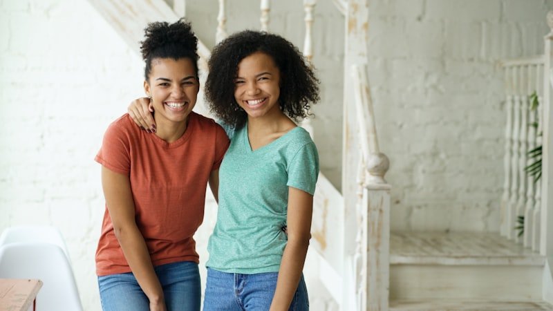Two smiling young women with arms around each other.