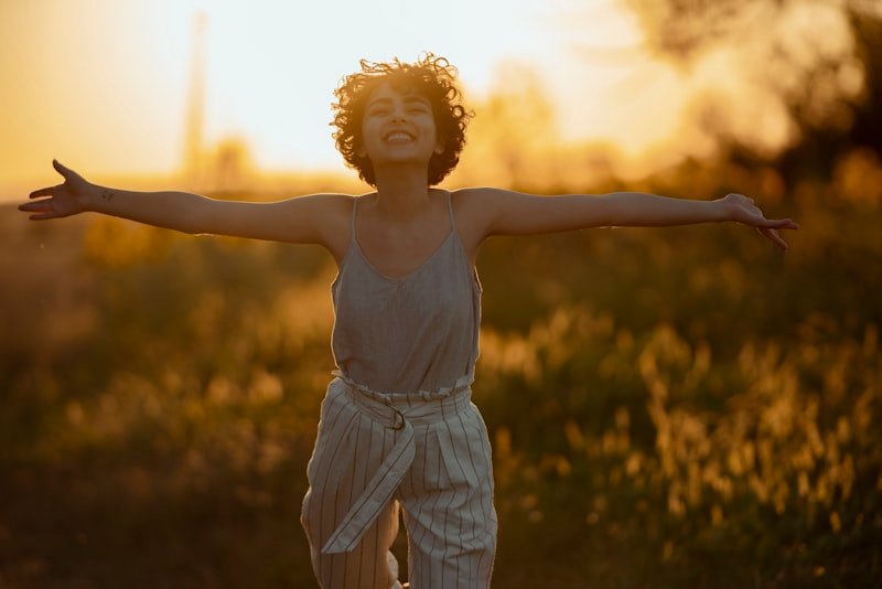 a woman standing in a field with her arms outstretched