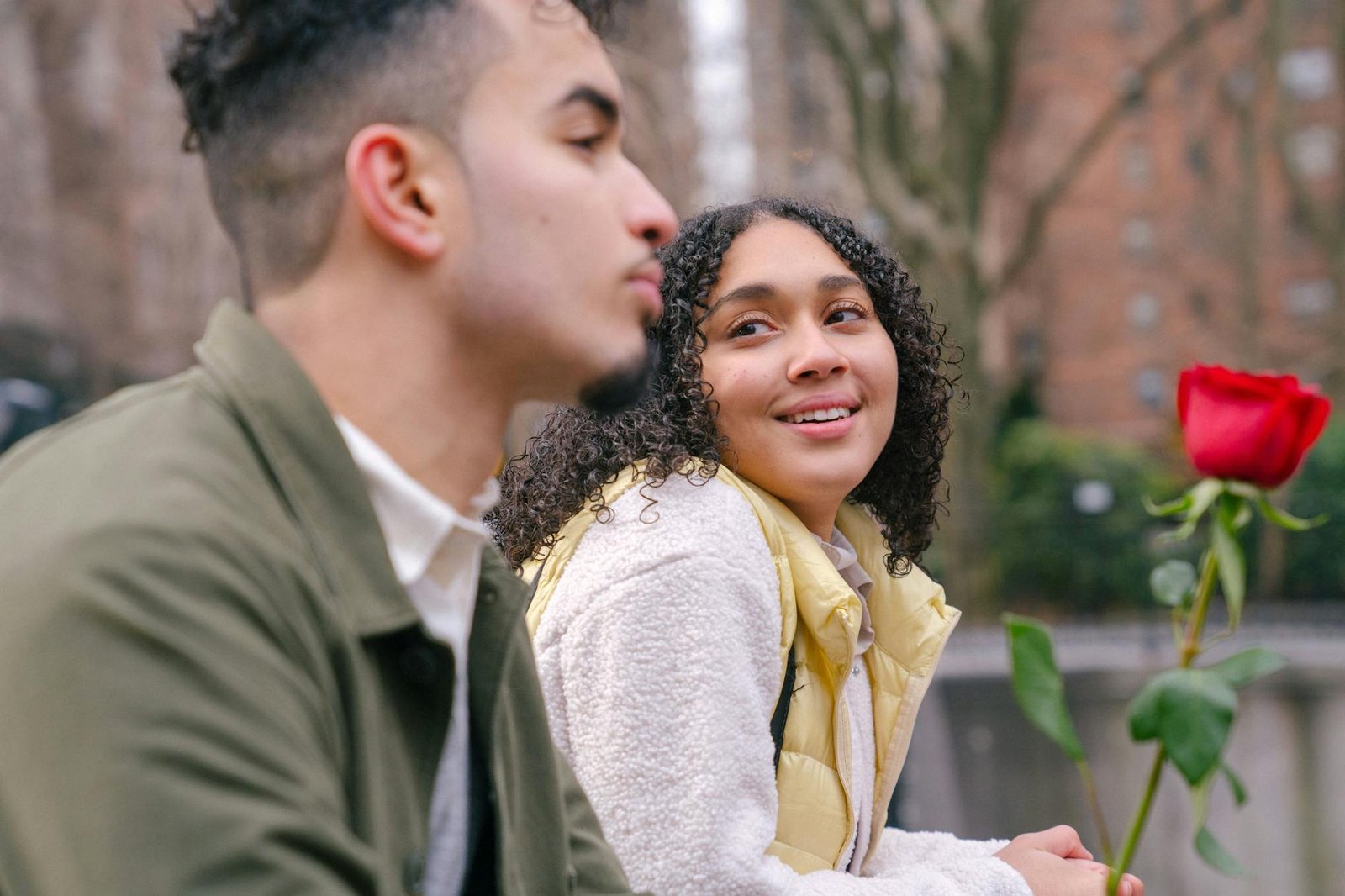 Young couple enjoying a romantic moment in an urban park holding a rose.