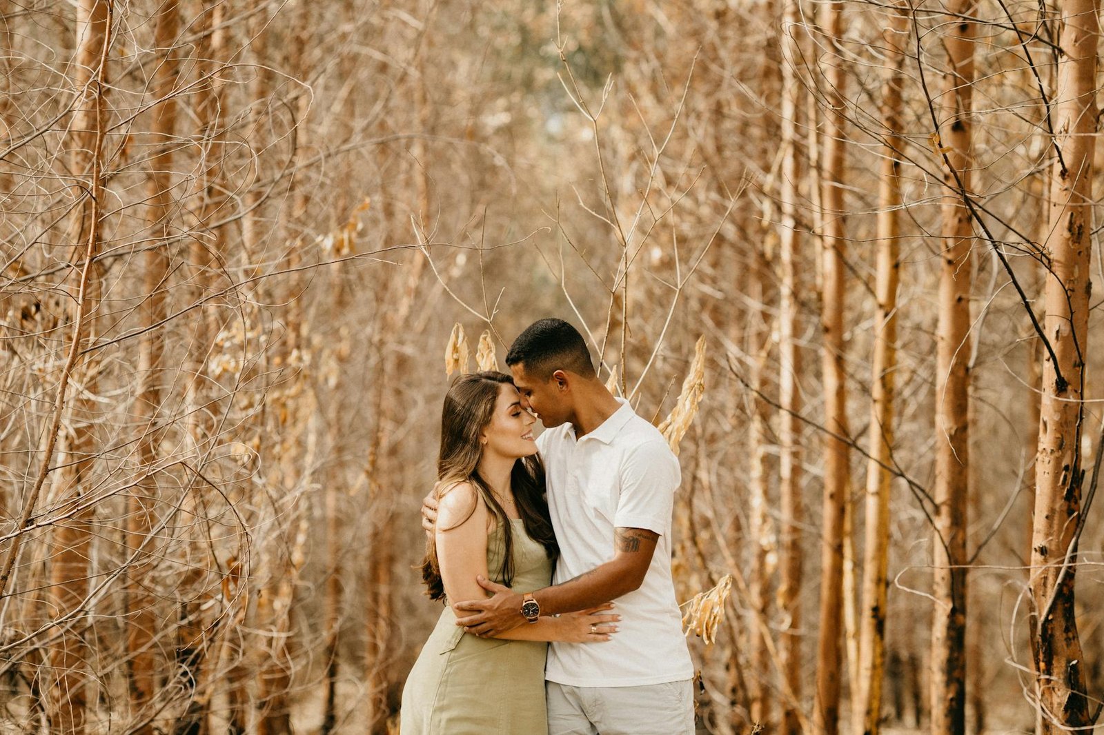 A loving couple shares a tender embrace in a serene autumn forest setting.