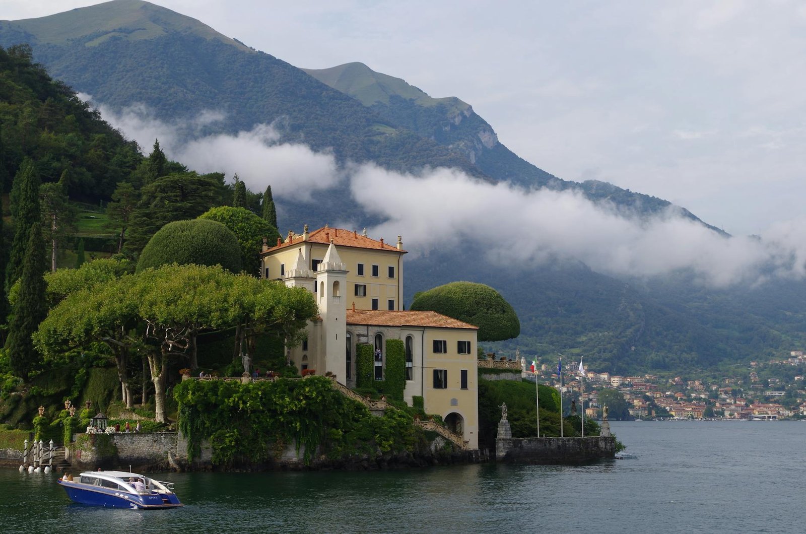 Scenic view of Villa del Balbianello by Lake Como, surrounded by lush hills and tranquil water.