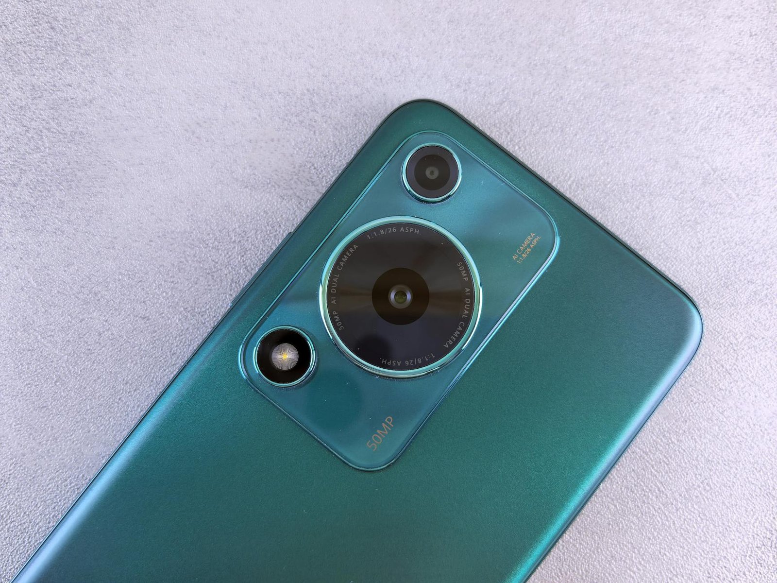 Detailed view of a smartphone camera lens on a sleek teal surface, showcasing contemporary design.