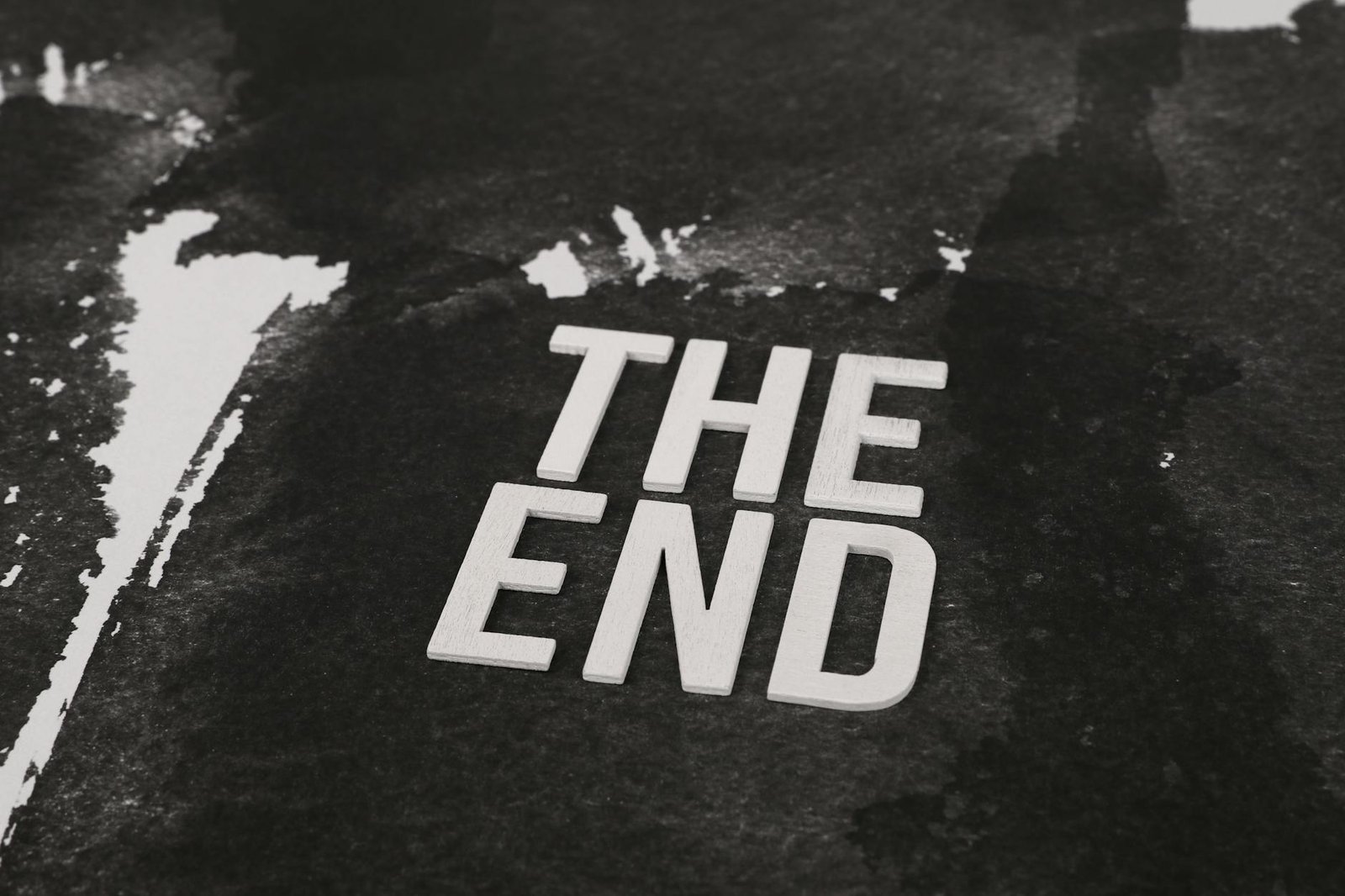Close-up of the phrase 'The End' in white text on a dark, textured background.