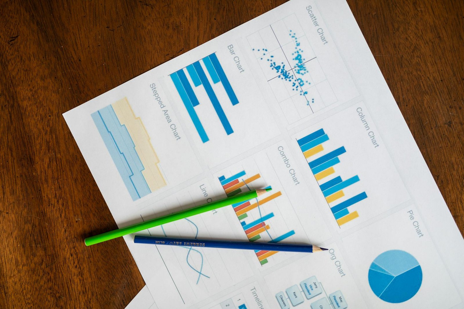 Top view of vibrant charts and colored pencils on wooden surface.