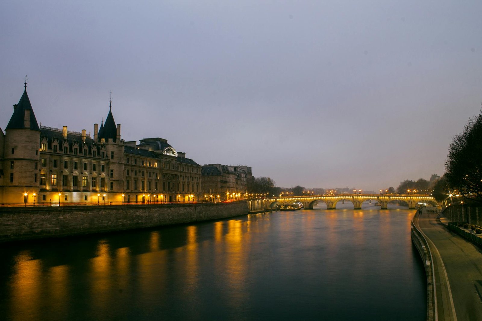 Serene dusk over the Seine River with historical Parisian architecture and bridge reflections.