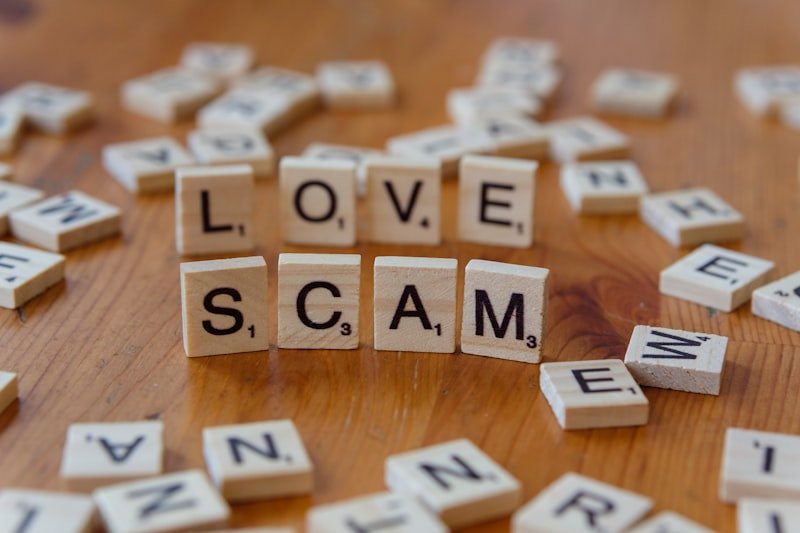 Scrabble letters spelling love scam on a wooden table