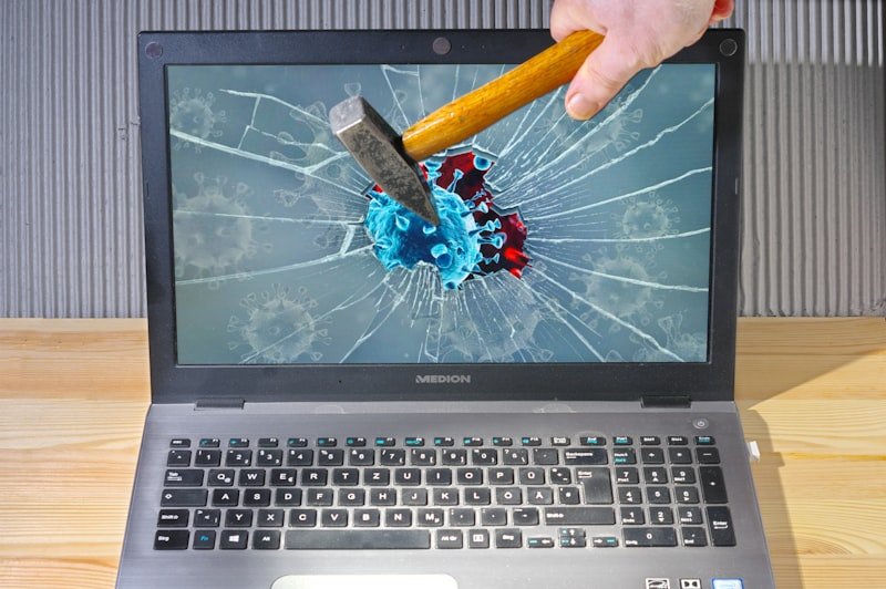 a person holding a pencil and a broken laptop
