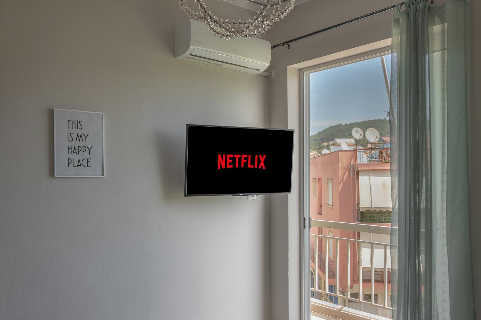 A comfortable room with Netflix on TV and window view of outside buildings.