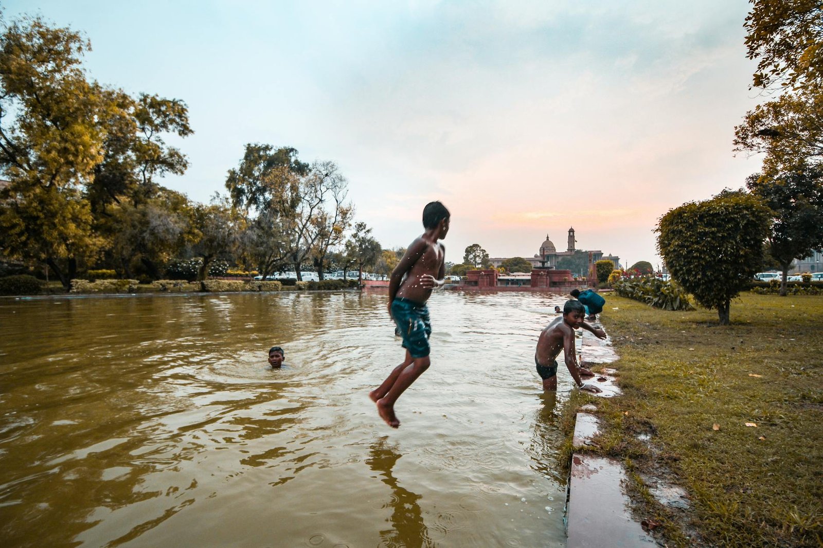 Joyful children playing by a lake, enjoying a warm day in India with scenic views.