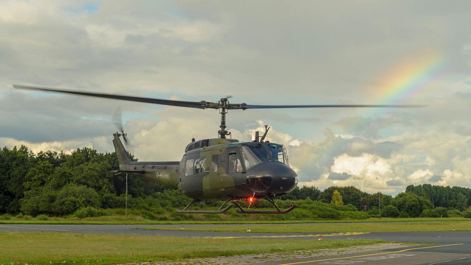 A military helicopter in flight with a vibrant rainbow overhead in Leer, Germany.