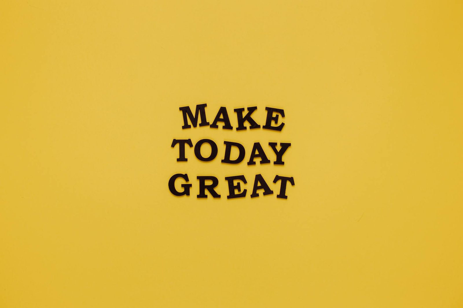 Simple and motivational quote 'Make Today Great' on a minimalist yellow background for inspiration.