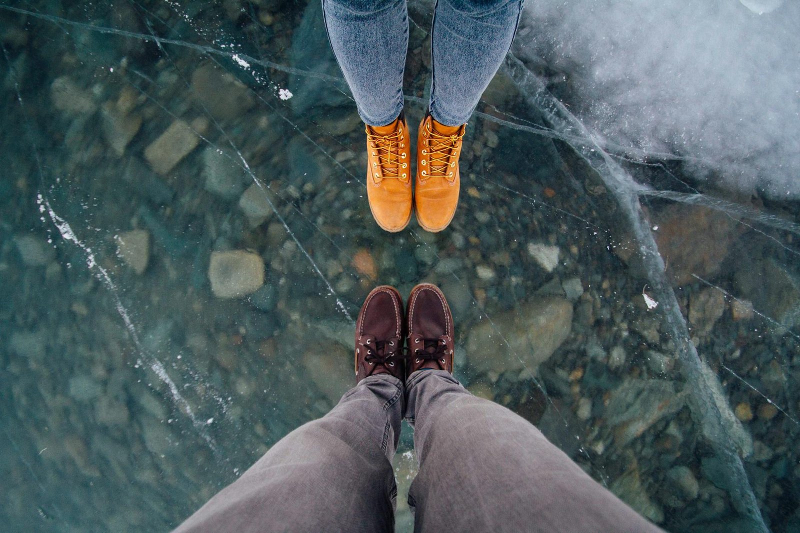Two people stand on a frozen lake showing their winter boots and jeans in Sachseln, Switzerland.