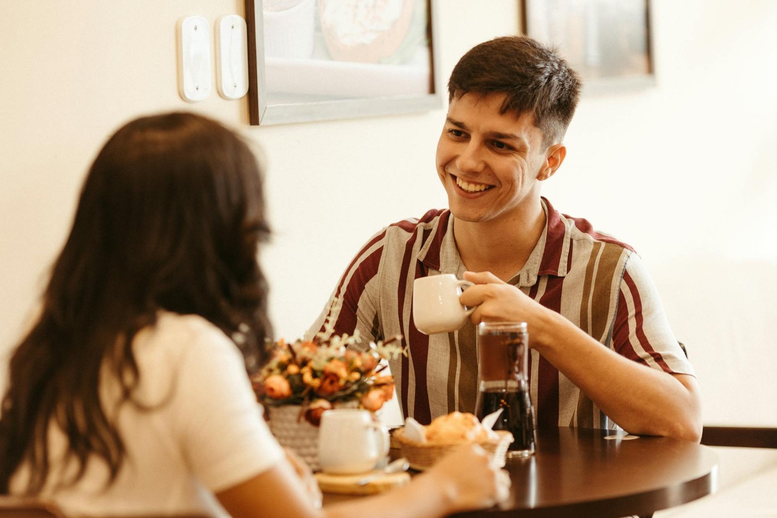 A couple shares a warm moment over coffee at a cozy cafe setting.
