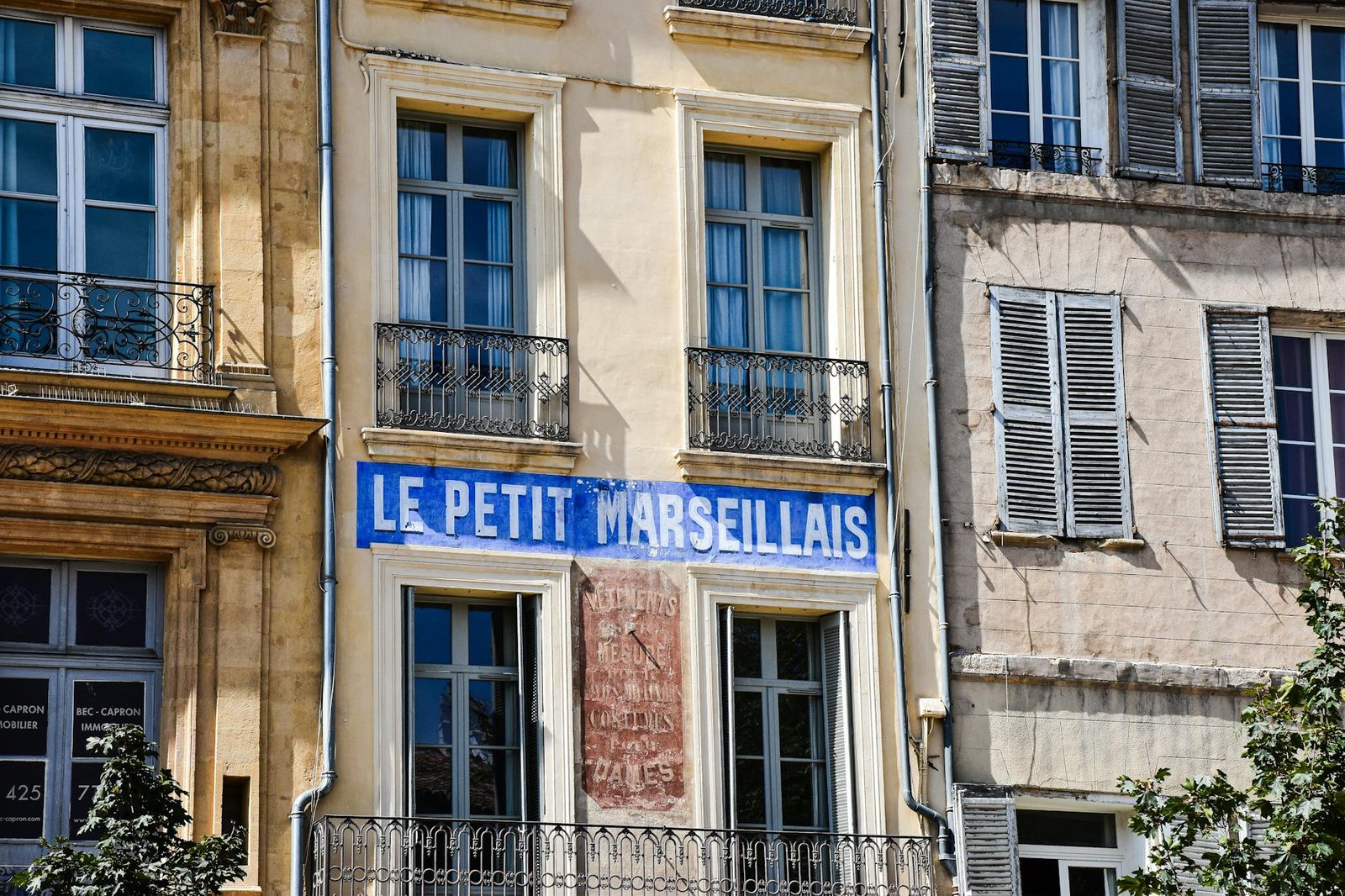 Charming building front with 'Le Petit Marseillais' in Aix-en-Provence, France.