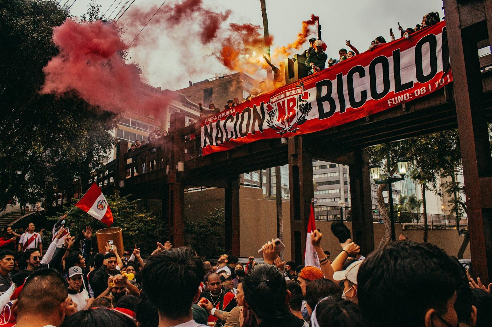 A dynamic protest scene in Lima with a crowd gathered under a red smoke-filled sky.
