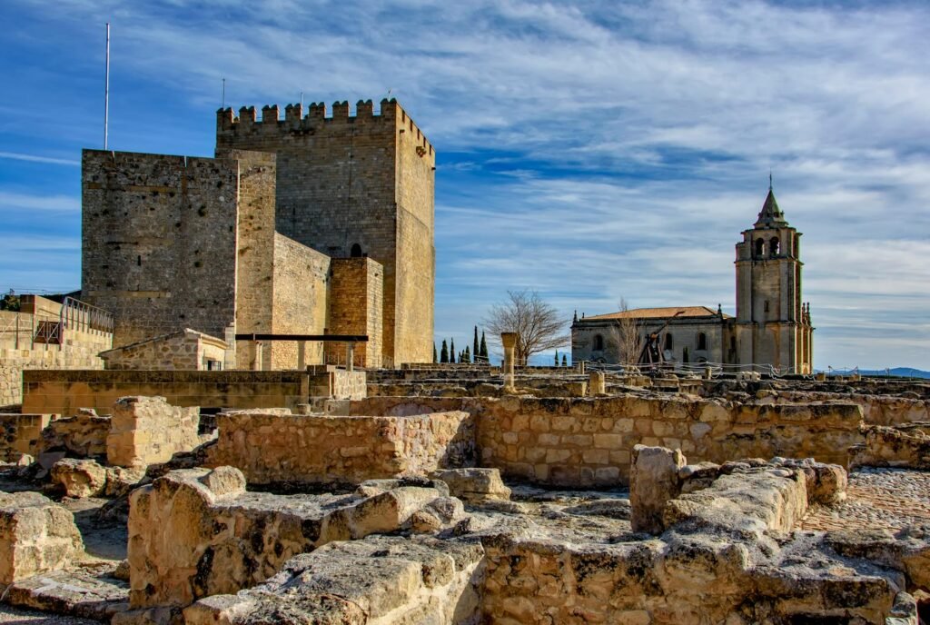 Explore the historic fortress and church under a clear blue sky in Alcalá la Real, Spain.