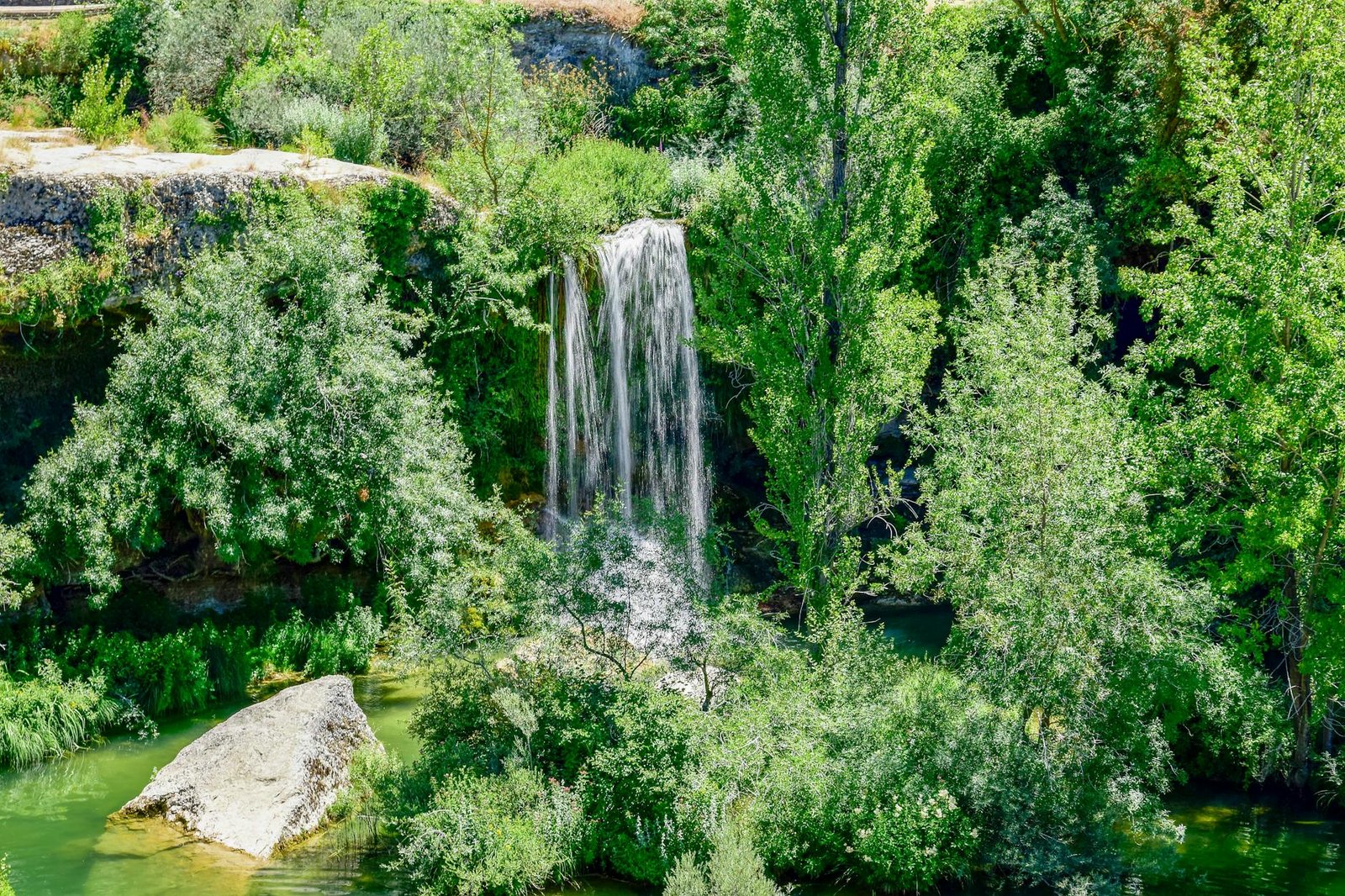 Stunning natural waterfall surrounded by lush greenery in La Orden, Spain.