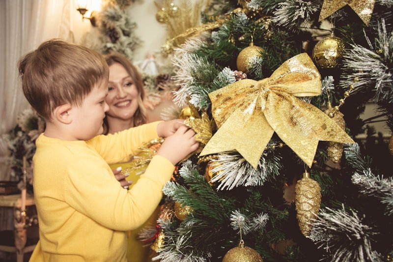 a woman and a child are decorating a christmas tree