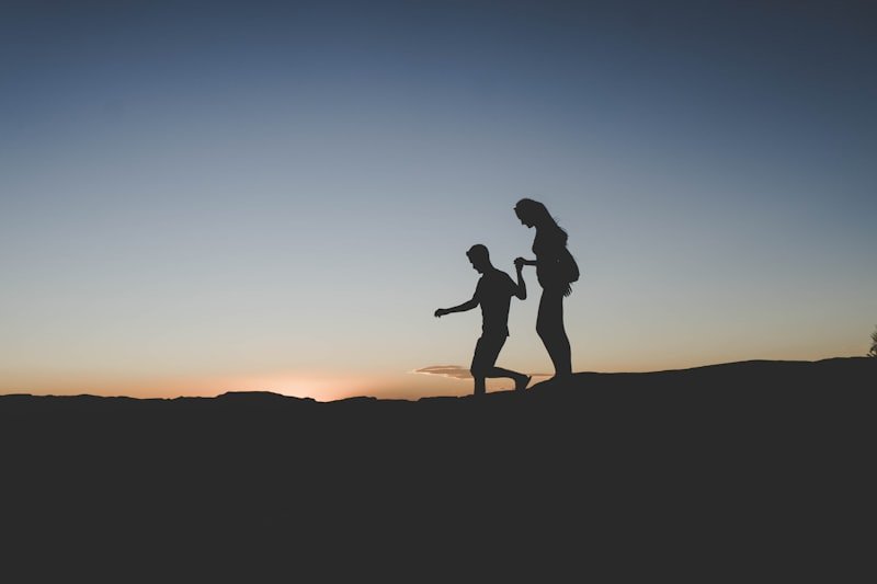 silhouette of man and woman walking on mountain