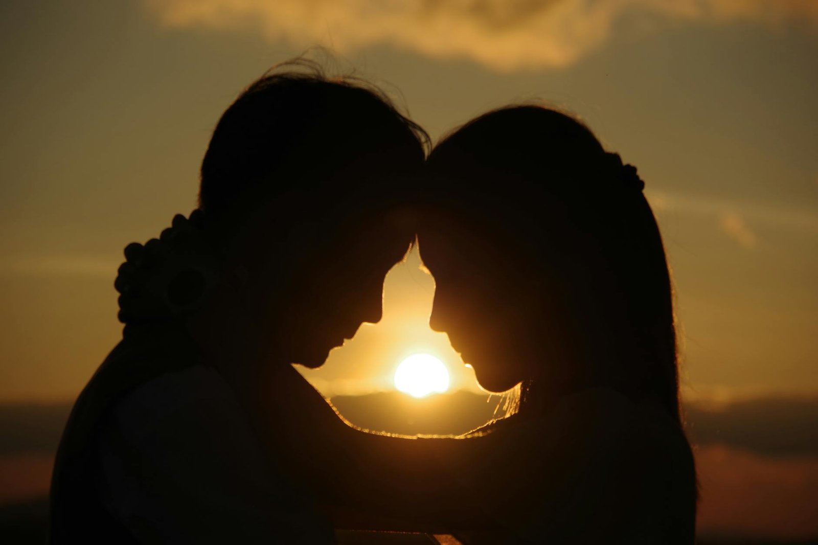 Silhouette of a couple embracing at sunset, capturing a romantic and intimate moment.