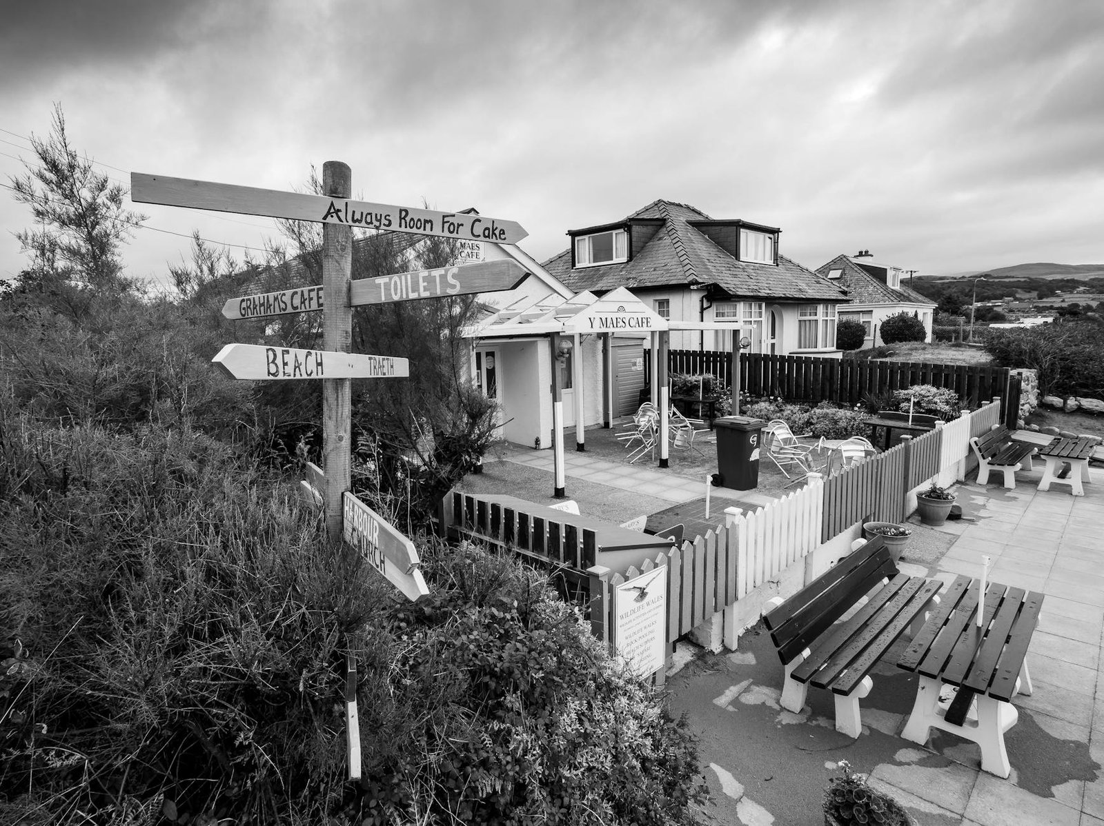 Black and white image of a quaint café and signpost in Llandanwg, Wales.