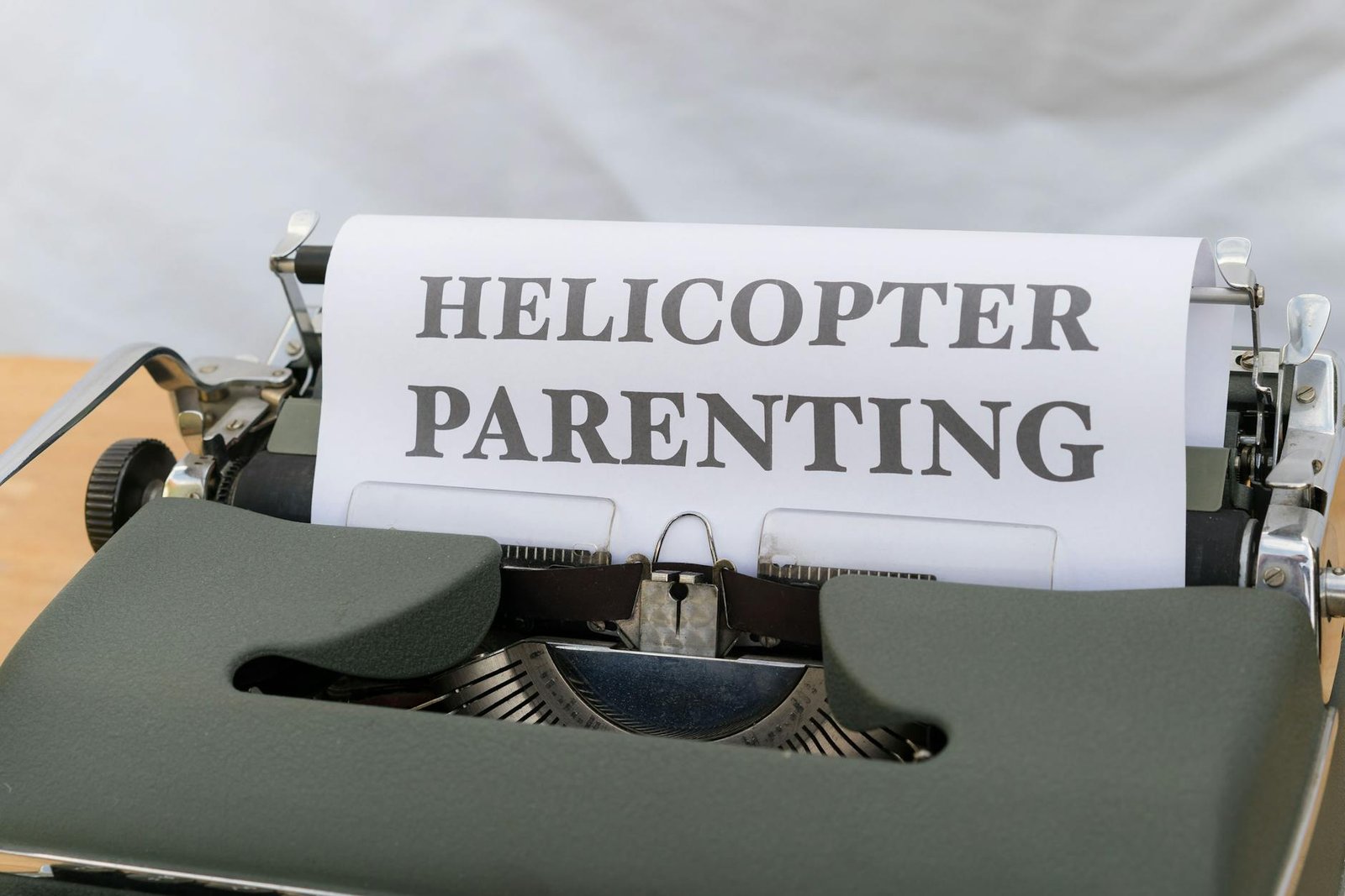 Close-up of a vintage typewriter displaying the concept of helicopter parenting on paper.