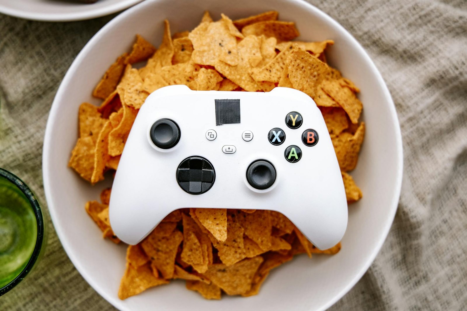 White Xbox controller resting on a bowl of nachos, perfect for gaming snack visuals.