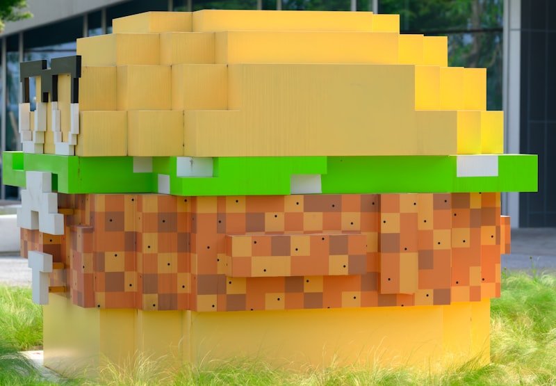 A giant lego hamburger sitting on top of a lush green field