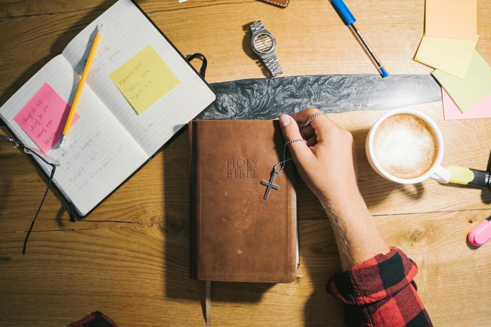 Top view of Bible study setup with coffee, notes, and wooden table.