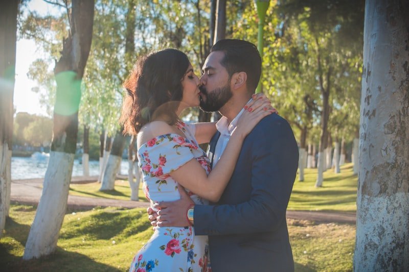 man in black suit kissing woman in white floral dress